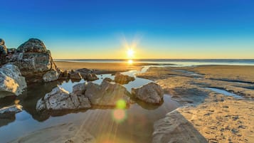 Una spiaggia con rocce e acqua che riflette il sole.