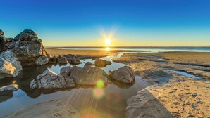 Una playa con rocas y agua reflejando el sol.