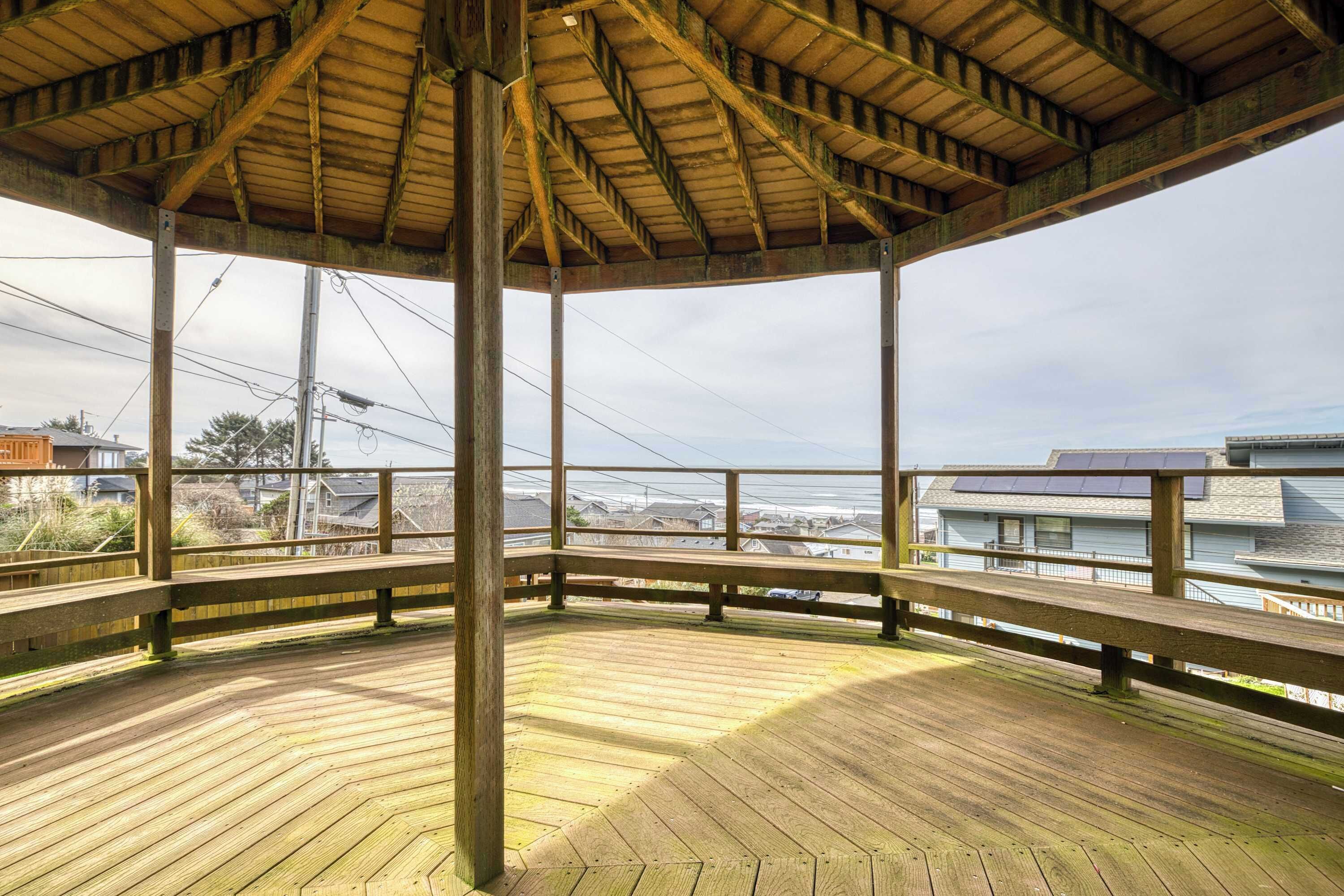 A covered wooden deck with a view of houses and power lines.
