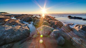 A rocky shoreline with the sun setting over the horizon. - Lovely Studio with Great View and Nearby Beach Access Dogs Welcome (Lincoln City)
