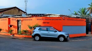 Un SUV plateado estacionado frente a un edificio de fachada roja y puerta de garaje cerrada.