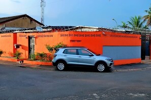 Un SUV plateado estacionado frente a un edificio de fachada roja y puerta de garaje cerrada.