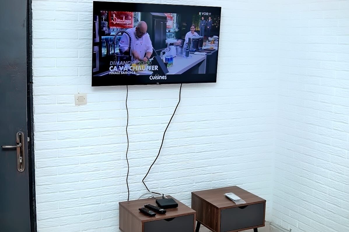 A television mounted on a white brick wall displaying a cooking show.