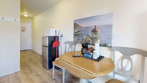 A small kitchen with a refrigerator, a coffee maker, and a painting of a coastal scene. - Lower Level Dog Friendly Studio with Ocean Views and Free WiFi Walk to Beach (Lincoln City)