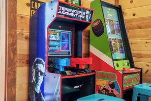 Spielautomaten mit den Aufschriften 'Terminator Judgment Day' und 'Donkey Kong', vor einer Holzwand.