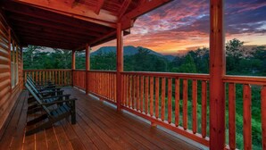 Eine Holzterrasse mit Bänken, mit Blick auf eine gebirgige Landschaft.