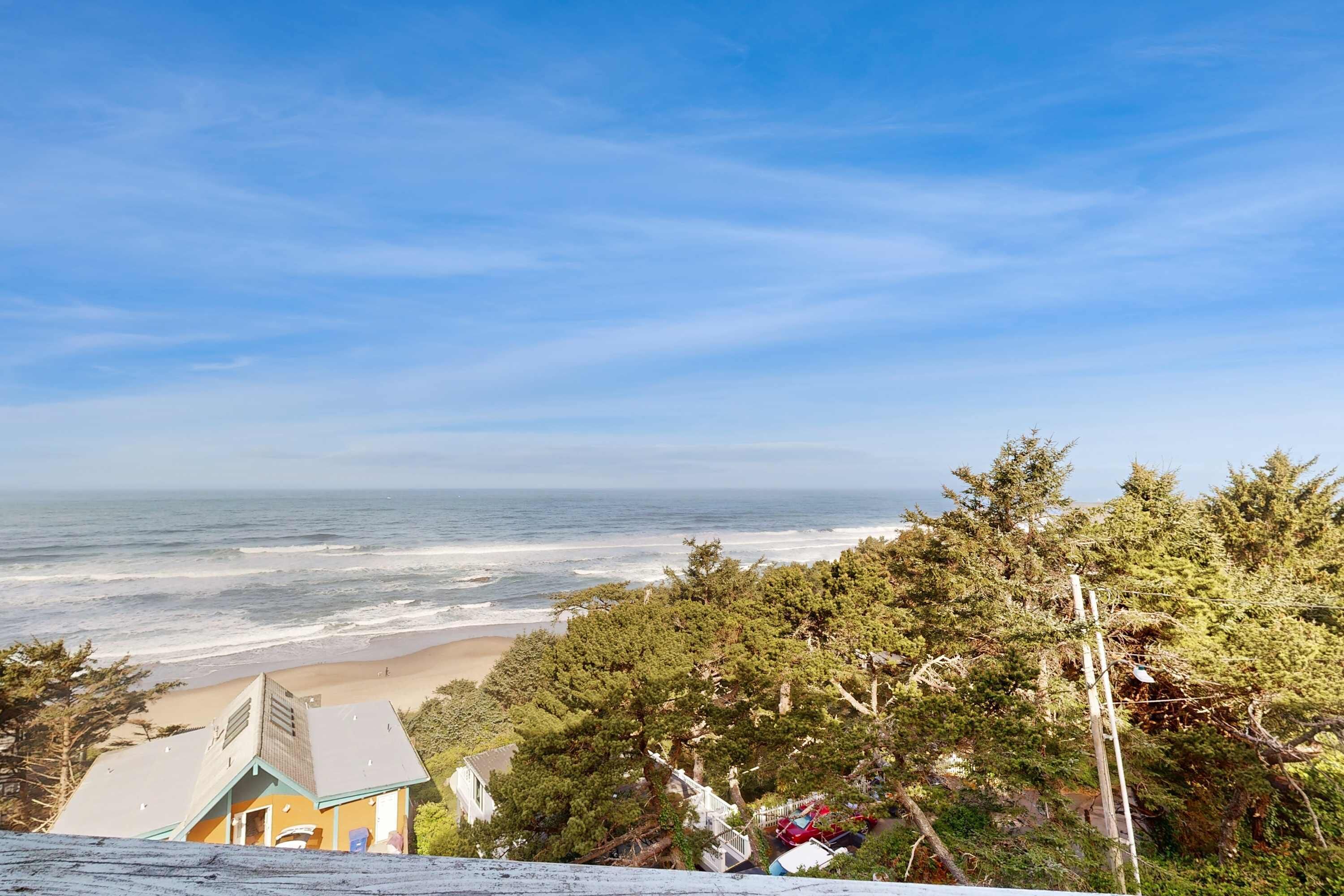A coastal view with a beach, ocean, and dense forest.