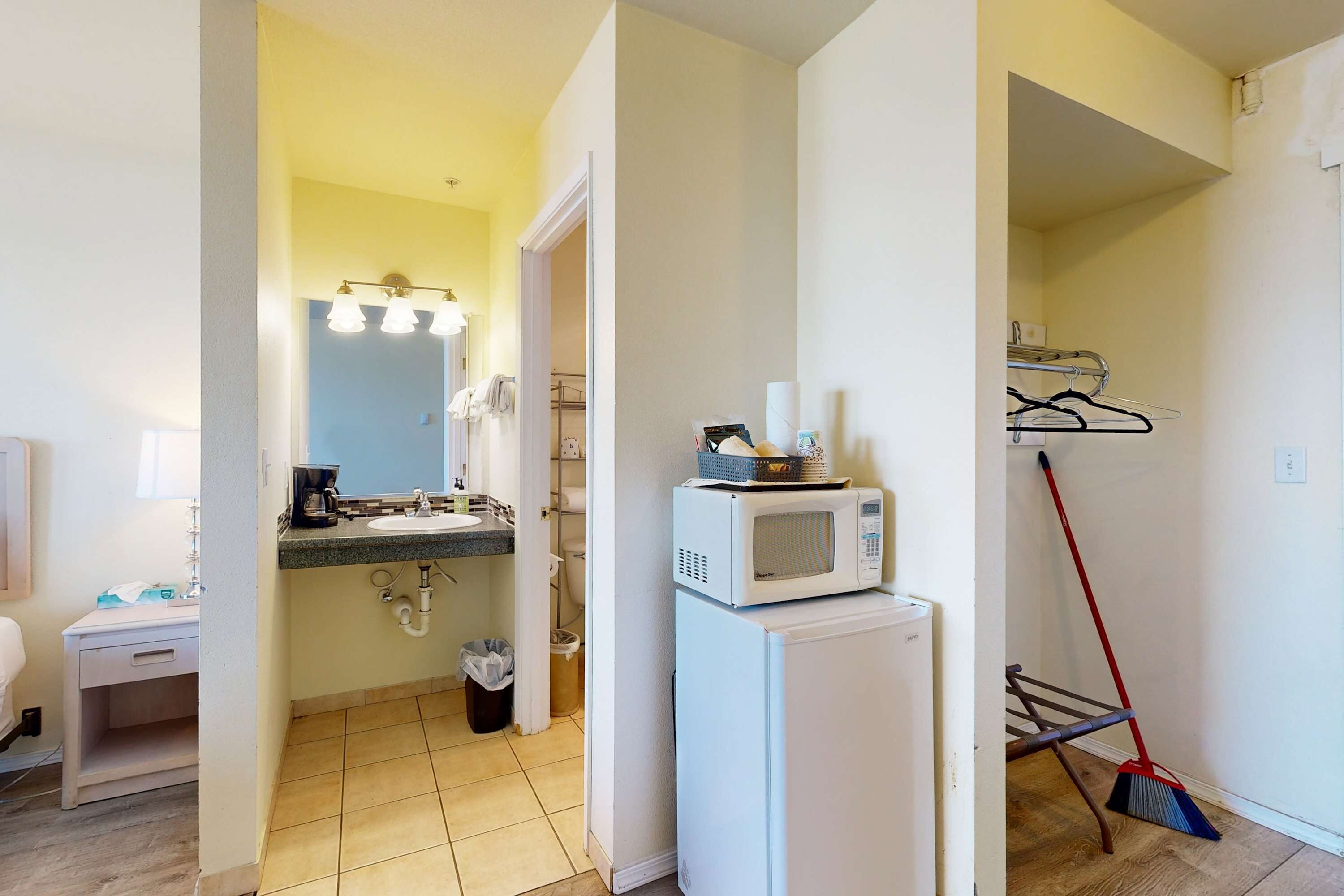 Une salle de bain équipée d’un lavabo, d’un miroir et d’un four à micro-ondes posé sur un meuble.