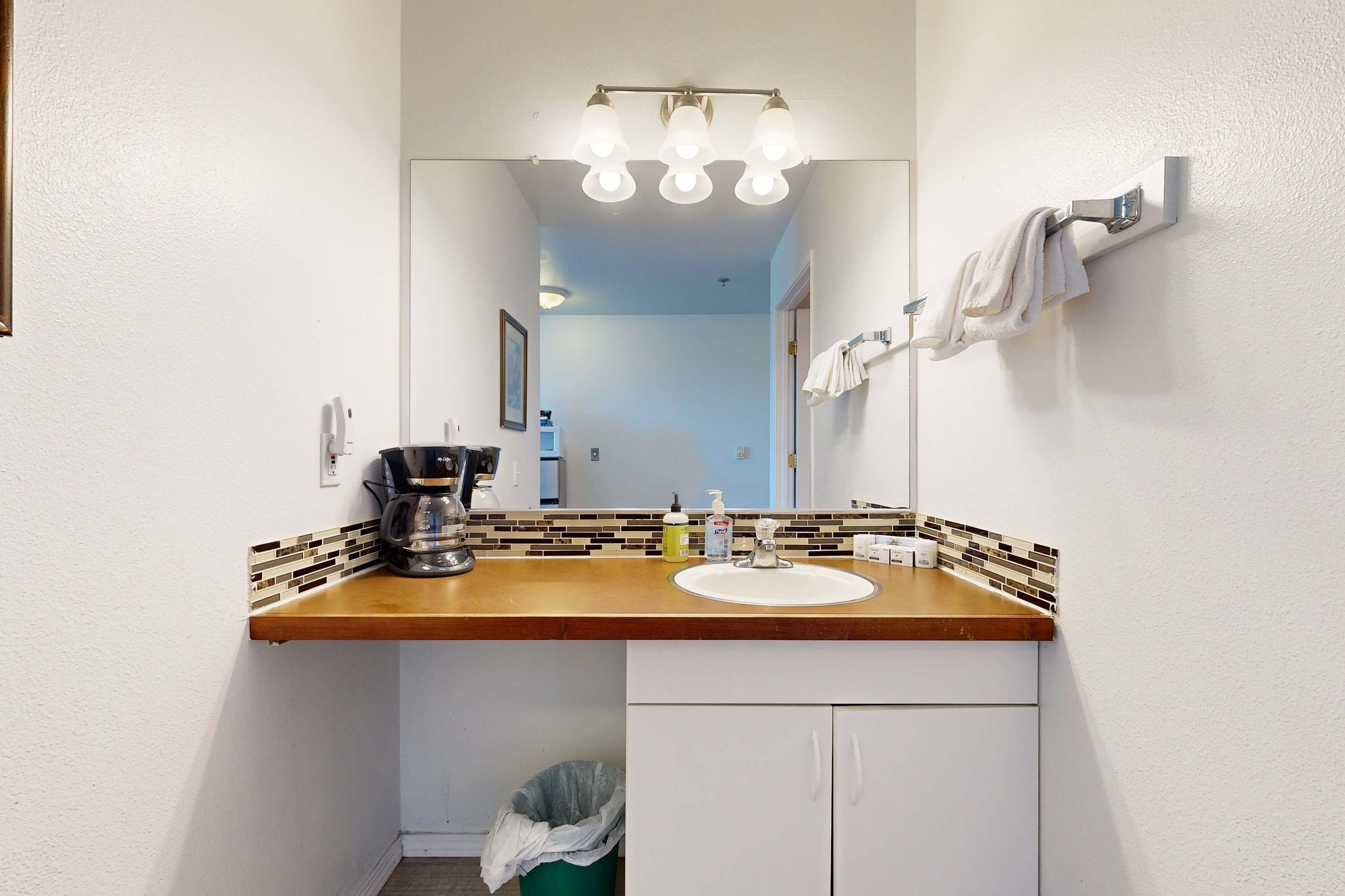 Ein Badezimmer mit einem Holzkosmetikschrank, einem Waschbecken, einem Spiegel und einem Handtuchhalter.