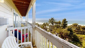 Un balcon avec vue sur l’océan, des balustrades blanches et un plafond en bois.