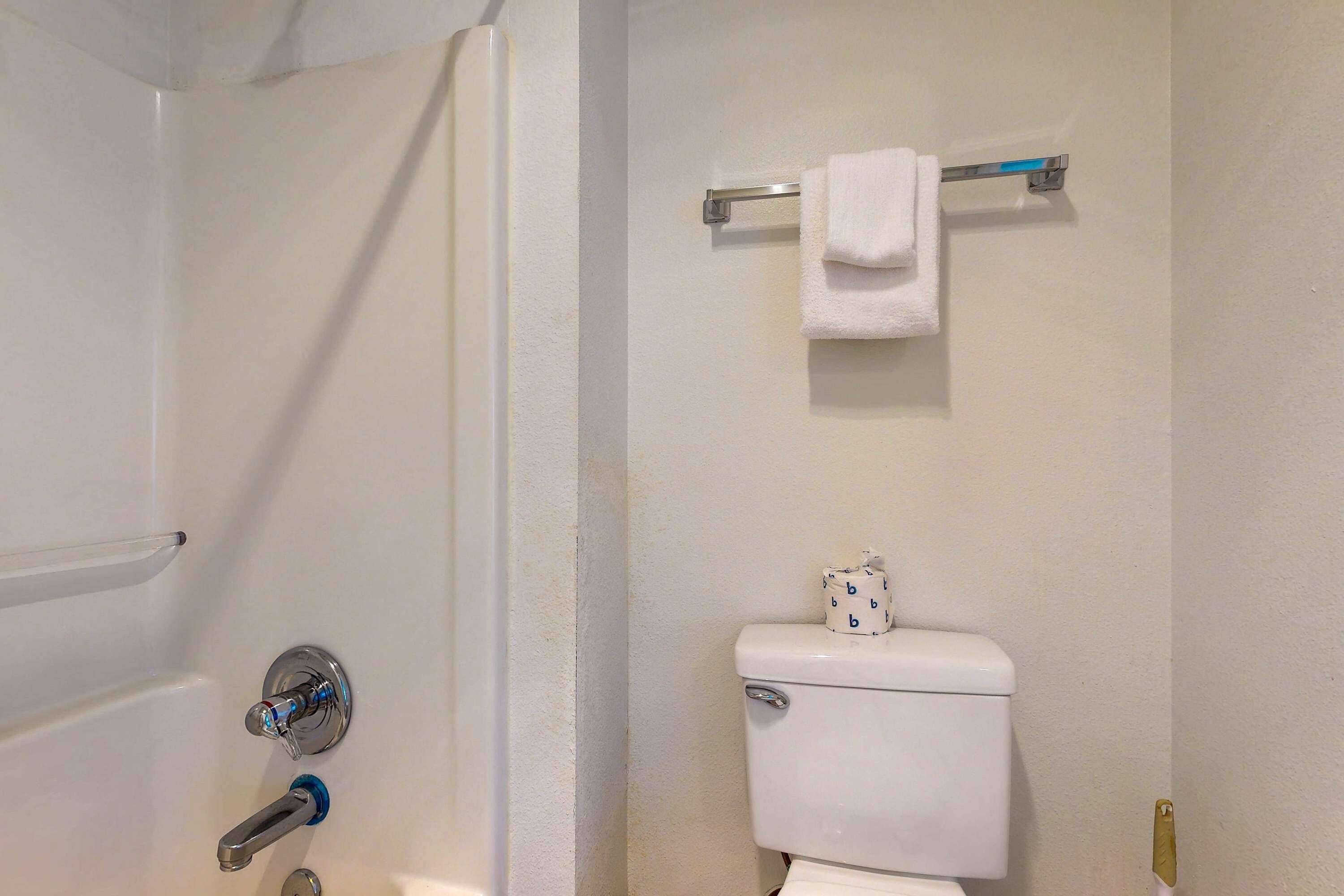 A bathroom with a white toilet, a towel rack with a white towel, and a shower area.
