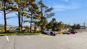 Un parking où sont garés un camionnette blanche et une voiture rouge, le tout entouré d’arbres, avec une enseigne de motel en arrière-plan.