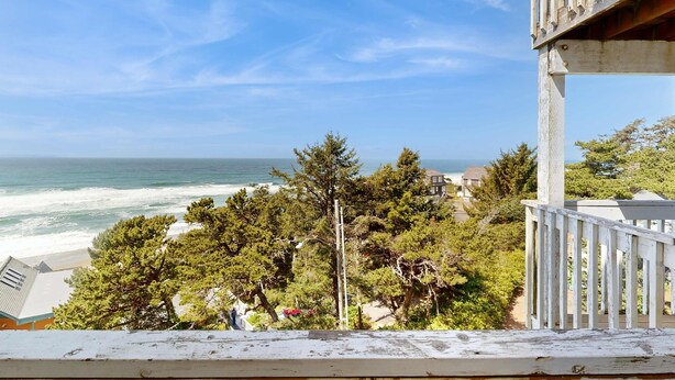 Une vue sur la côte, avec un balcon en bois donnant sur l’océan et la plage.
