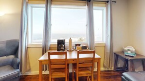 Una habitación con una mesa de madera, dos sillas, un sofá y una mesita con una cesta.