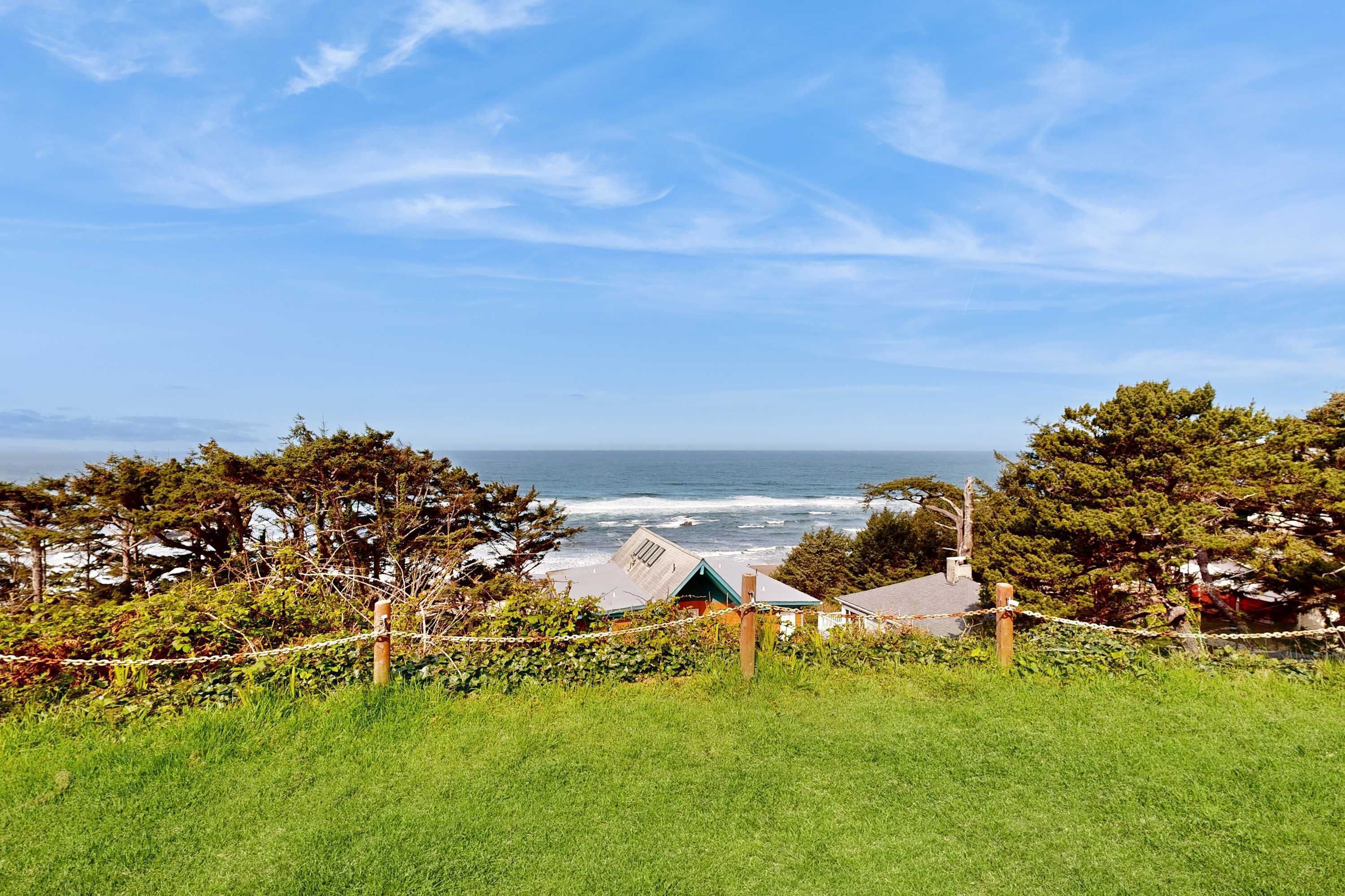 A coastal landscape with a grassy foreground, a small building, and a view of the ocean.