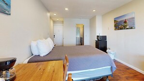 Une chambre d’hôtel avec un lit, une table en bois, un four à micro-ondes et un tableau au mur.