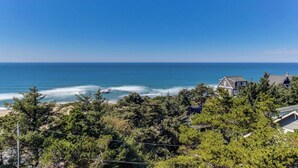 A coastal property with a view of the ocean, surrounded by dense greenery and a house with a gabled roof. - Upper Level Studio with Sweeping Ocean Views Dog Friendly (Lincoln City)