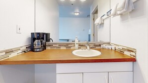 A bathroom with a wooden countertop, a white sink, a coffee maker, and a mirror with a towel rack. - Upper Level Studio with Sweeping Ocean Views Dog Friendly (Lincoln City)