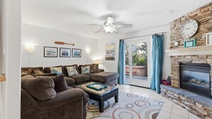 Ein Wohnzimmer mit Sofa, Couchtisch, Kamin und Deckenventilator.
