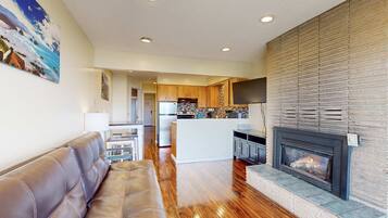 A modern living room with a leather sofa, a fireplace, and a kitchen in the background.