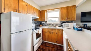 Une cuisine moderne avec des meubles en bois, un réfrigérateur blanc, une cuisinière, un four à micro-ondes et un évier.