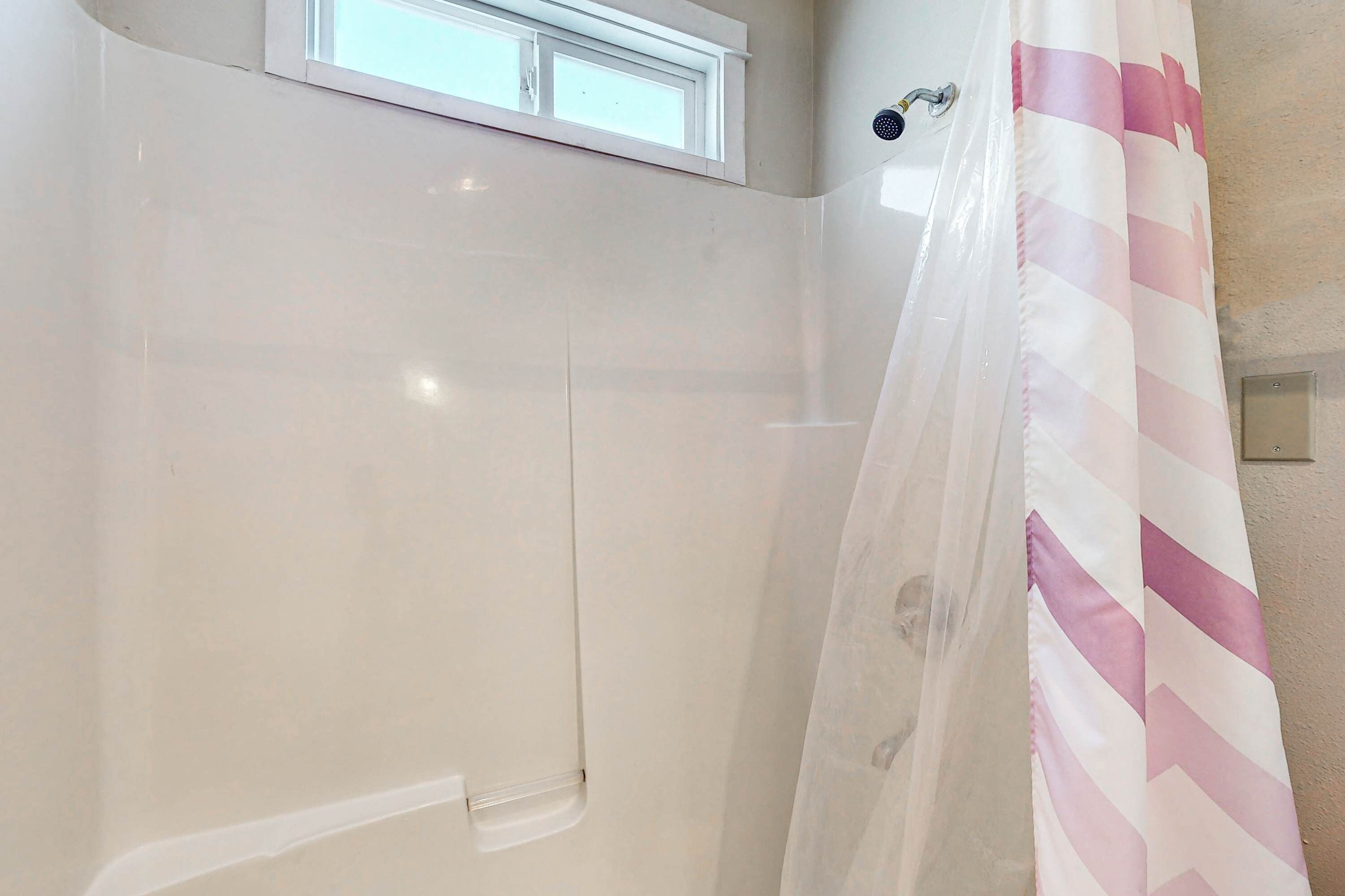 Een badkamer met een douche, een raam en een douchegordijn met strepen.