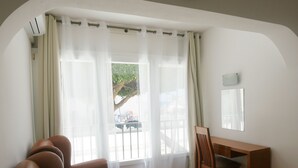 A room with a large window, a wooden desk, a chair, and a sofa. - Dom Sancho Carvoeiro Beach Apartment Luxury (Carvoeiro)