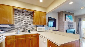 A modern kitchen with wooden cabinets, a tiled backsplash, a microwave, and a built-in oven. - Dog Friendly Oceanview Condo with Great Location and Nearby Beach Access (Lincoln City)