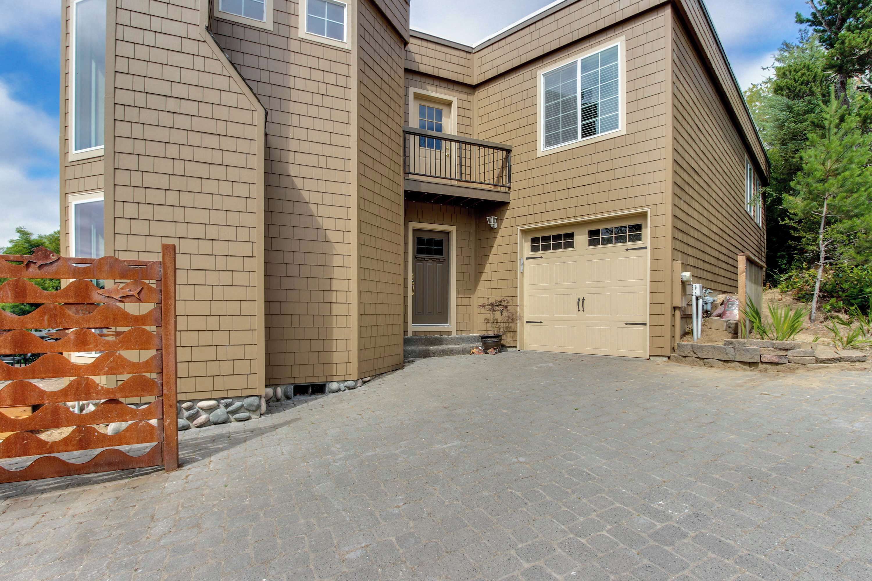 A two-story house with a garage, a balcony, and a paved driveway.