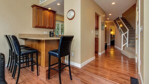 A kitchen with wooden cabinets, a clock, and a bar area with stools. - Dog Friendly Lakefront Vacation Home with Stunning Views and Spacious Deck (Lincoln City)