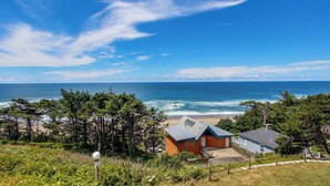 Una propiedad costera con vista al mar, una casa pequeña y árboles circundantes.