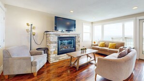 Una sala de estar con chimenea de piedra, televisor de pantalla plana y sofá con almohadas amarillas.