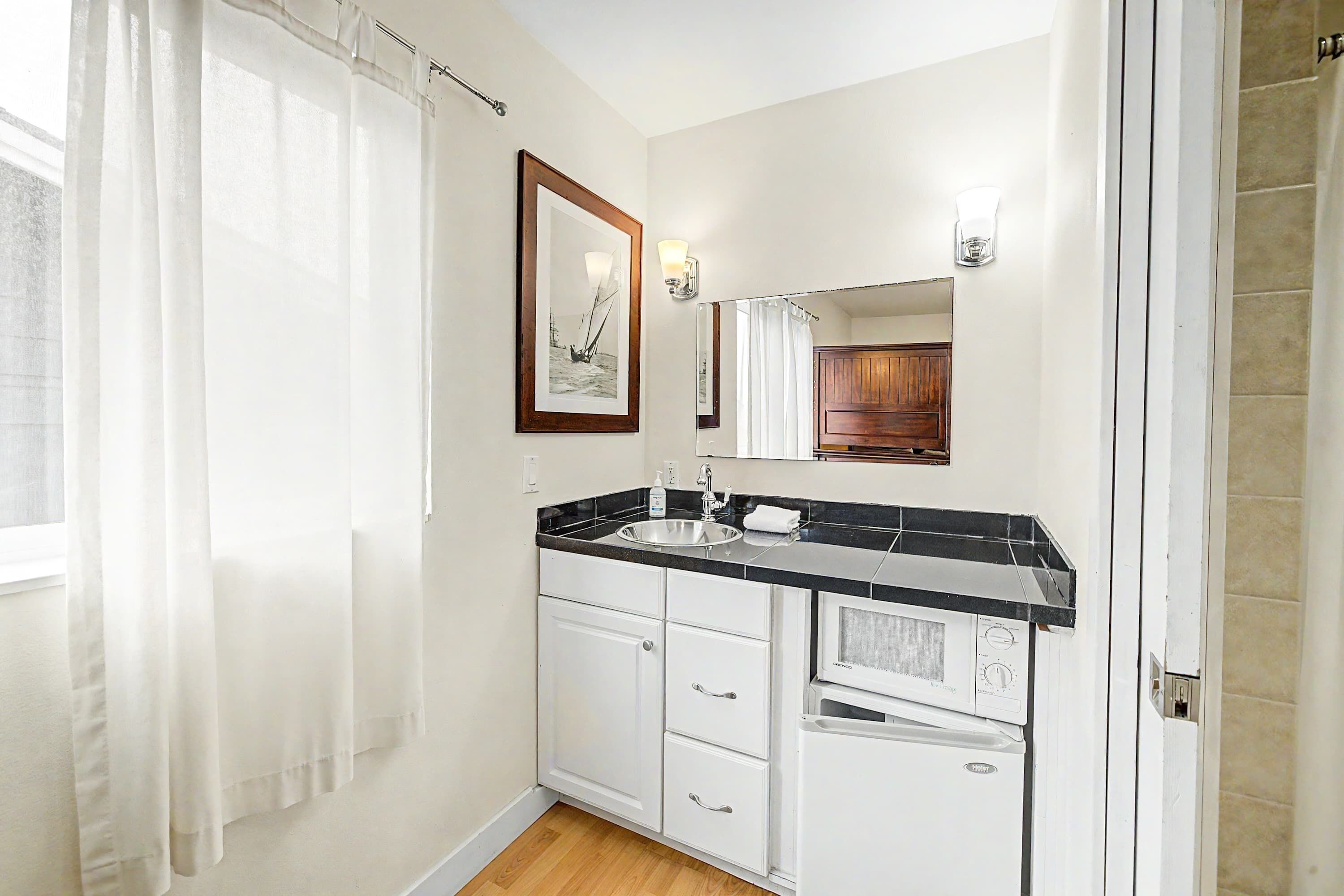 A bathroom with a sink, mirror, and a framed picture on the wall.
