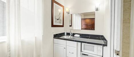 A bathroom with a sink, mirror, and a framed picture on the wall.