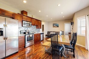 A modern kitchen with stainless steel appliances, wooden cabinets, and a dining area with a wooden table and black chairs. - Huge Renovated Condo with Ocean Views and Nearby Beach Access Dog Friendly (Lincoln City)