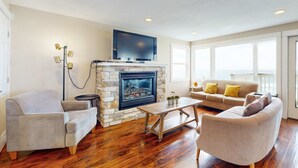 Una sala de estar con chimenea de piedra, televisor de pantalla plana, sofá y mesa de centro.