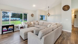 Una sala de estar moderna con un sofá modular, una estantería y un amplio ventanal con vistas al exterior.