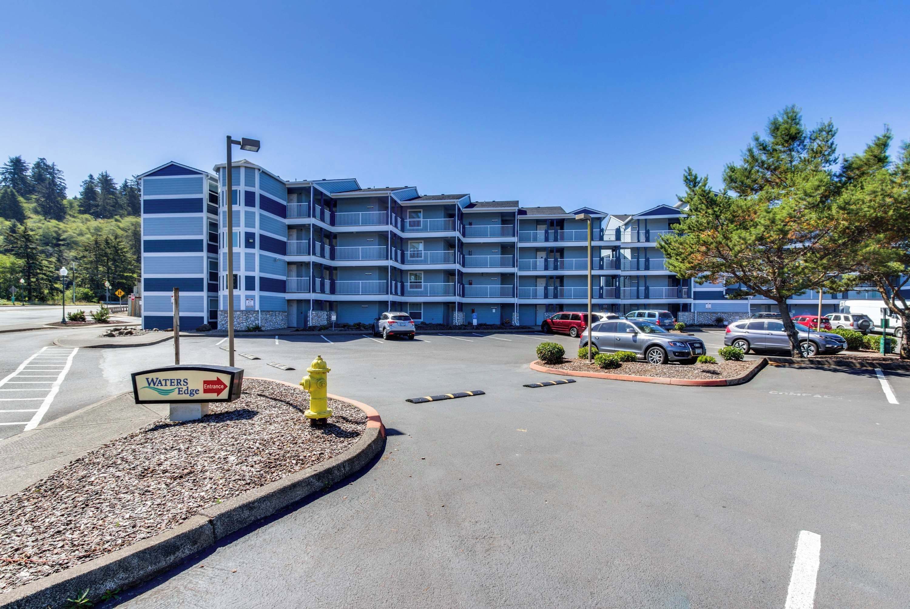 A multi-story hotel with a parking lot in front.