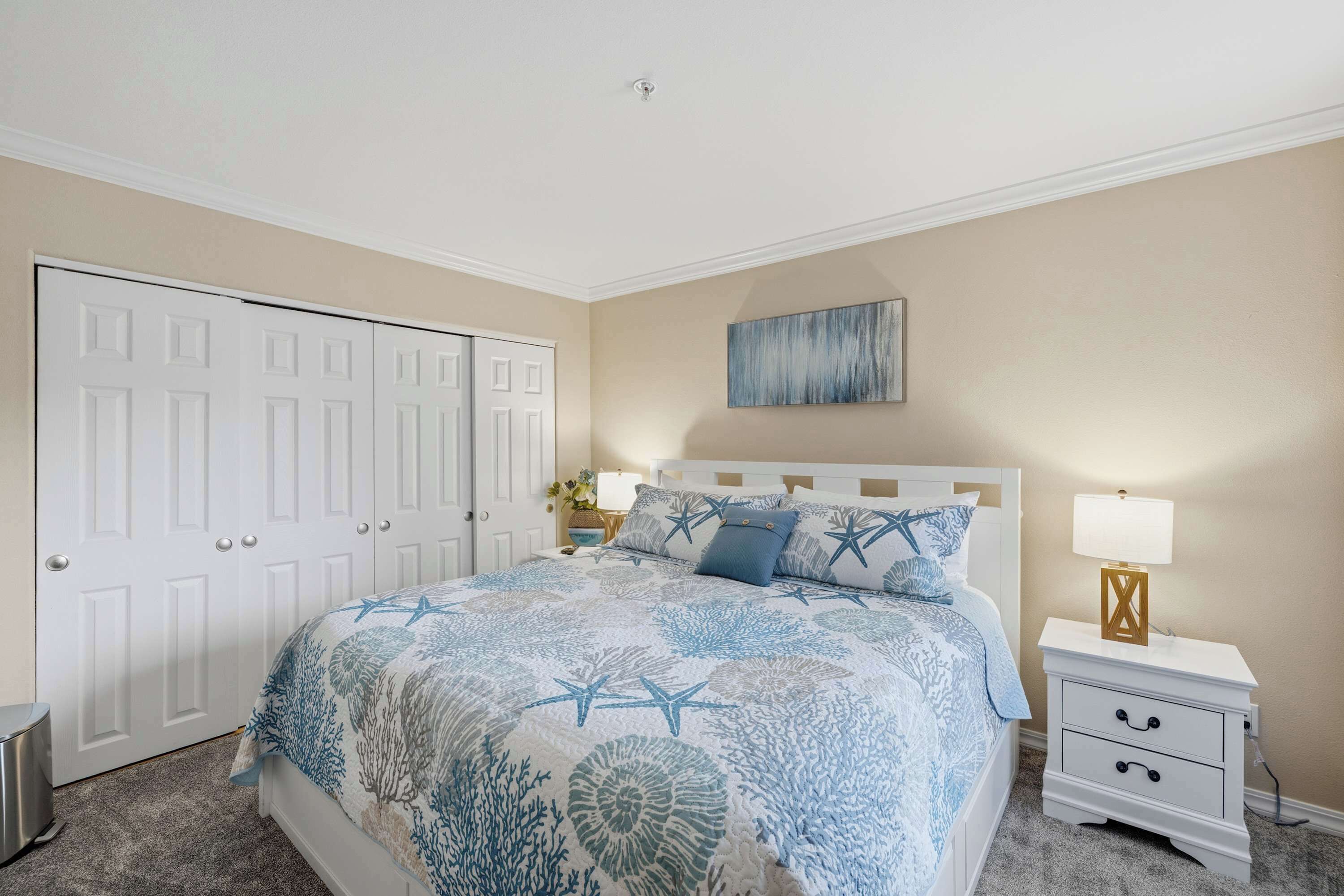 A bedroom with a bed, nightstand, dresser, and a painting on the wall.