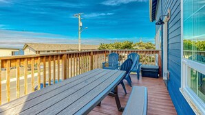 A wooden deck with a table and chairs, overlooking a street and houses. - Dog friendly home with ocean views hot tub deck foosball and fireplace (Lincoln City)