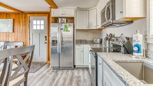 A modern kitchen with white cabinets, a stainless steel refrigerator, a microwave, and a granite countertop. - Dog friendly home with ocean views hot tub deck foosball and fireplace (Lincoln City)