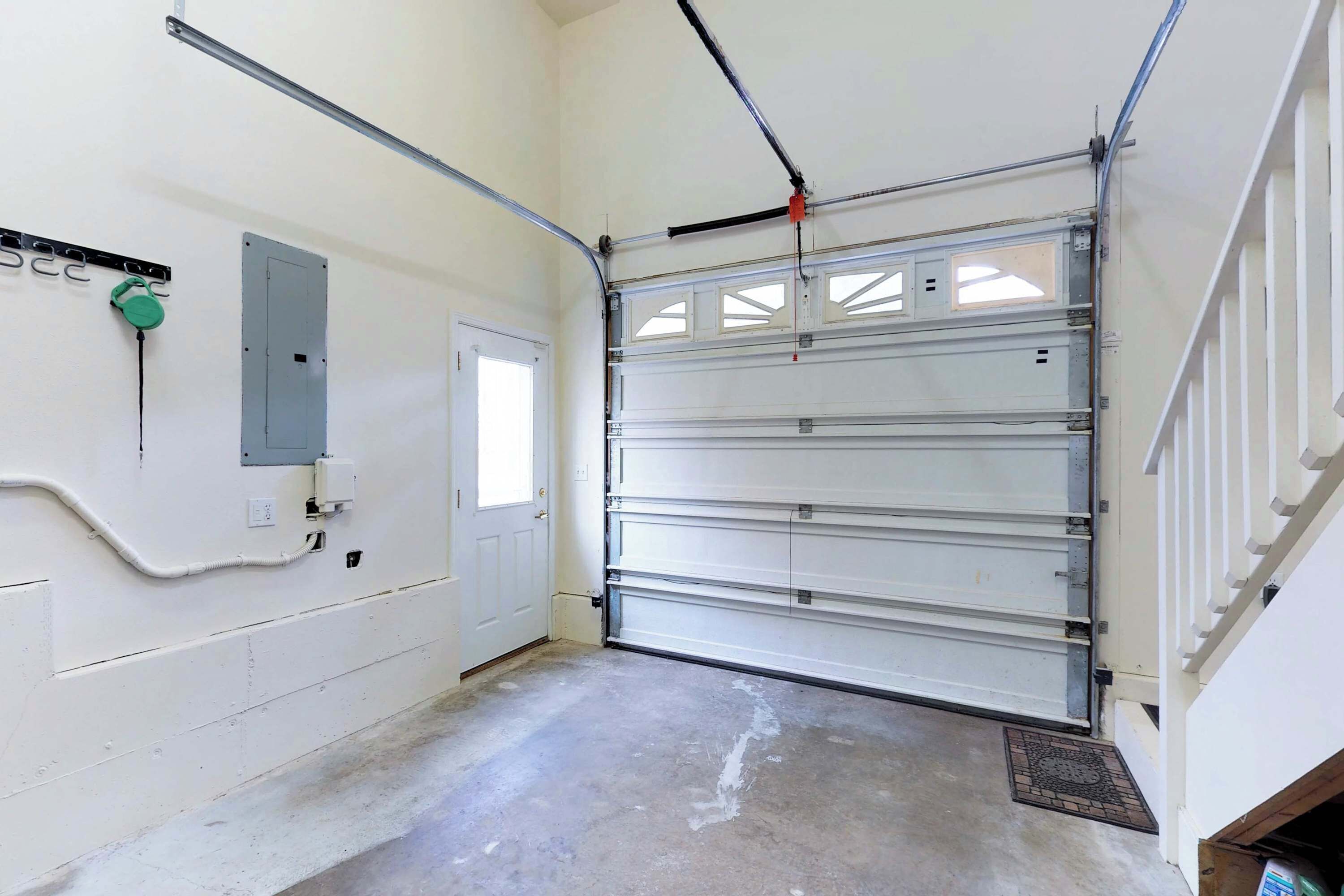 A garage with a white door, a control panel, and a concrete floor.