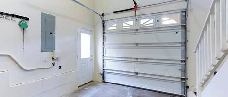 A garage with a white door, a control panel, and a concrete floor.