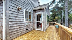 A wooden deck with a railing, a sliding glass door, and a window. - Spacious dog friendly home with WiFi and fireplace near the beach (Lincoln City)