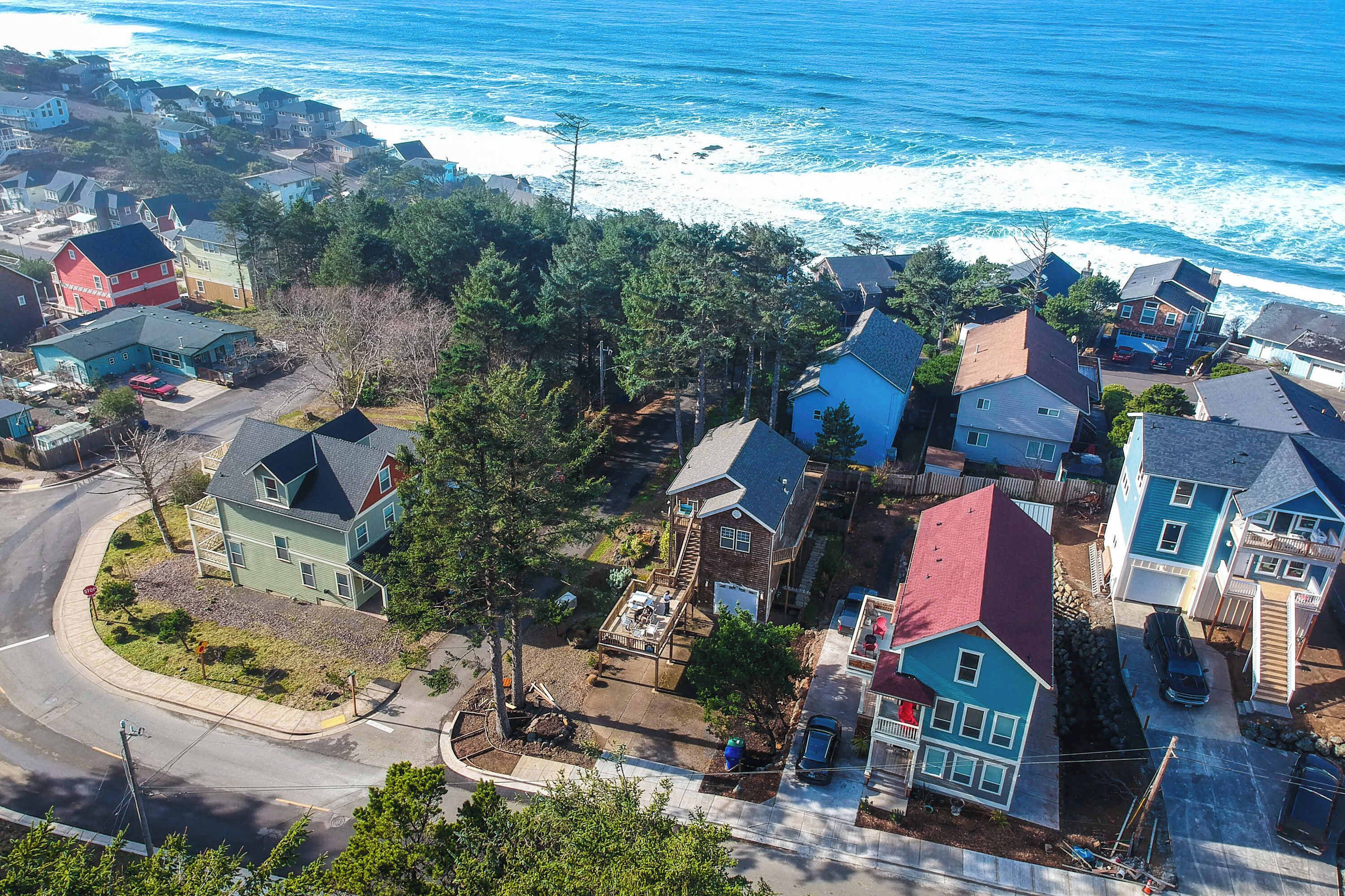 A coastal residential area with houses, a road, and a beach in the background.