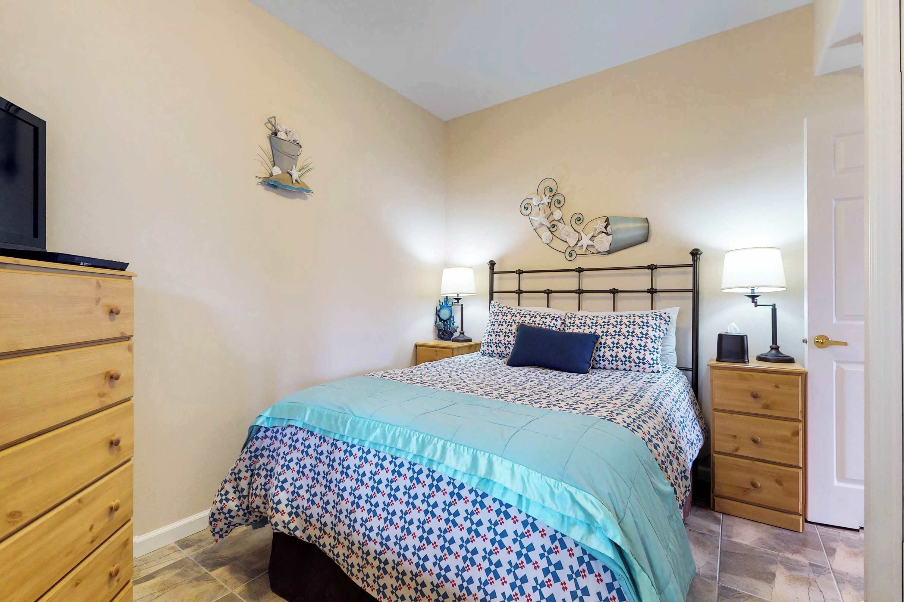 A bedroom with a bed, two bedside tables, a dresser, and a TV.