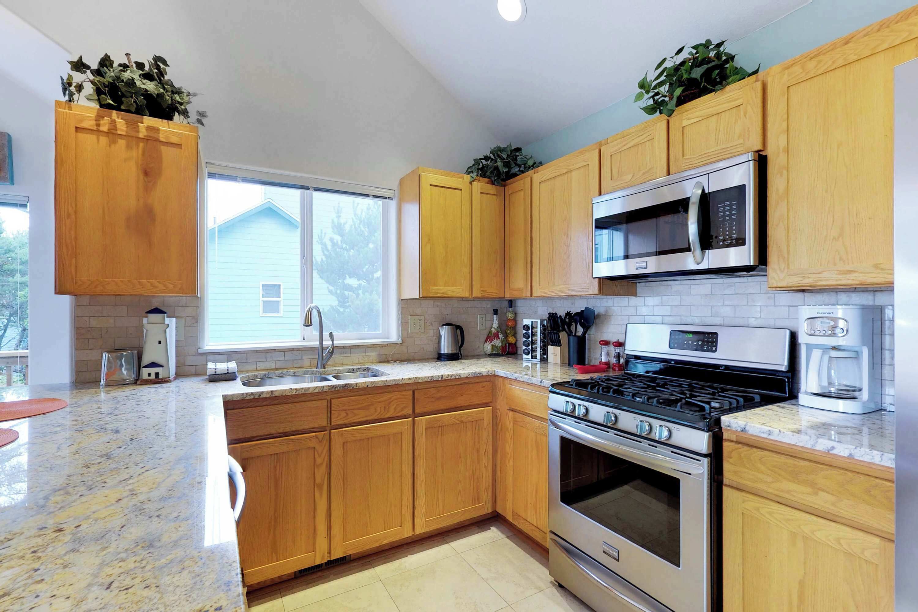 A modern kitchen with wooden cabinets, stainless steel appliances, and a large window.