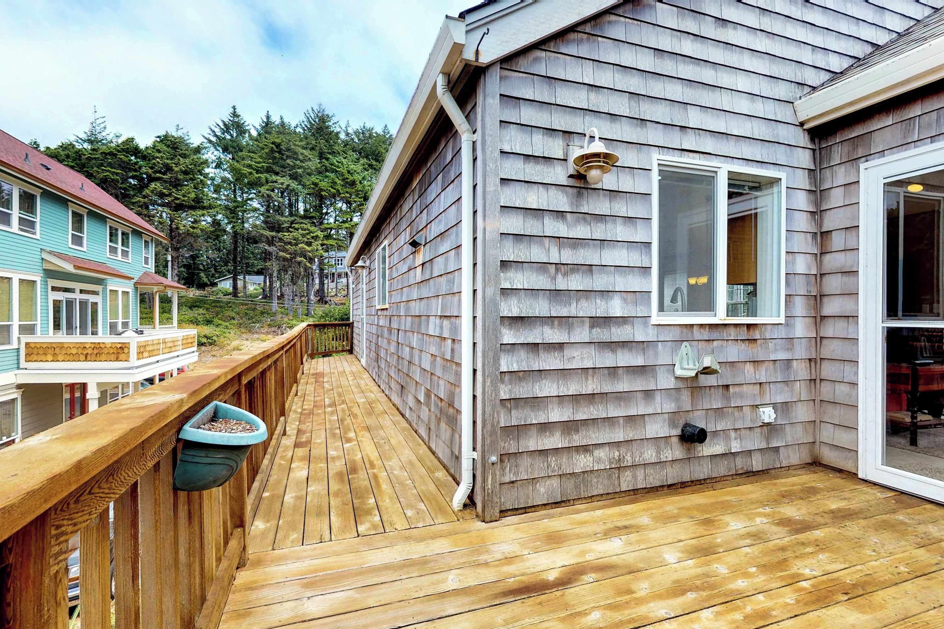 A wooden deck with a railing, a window, and a light fixture on a house with siding.