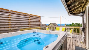 Ein Whirlpool auf einer Holzdielen-Terrasse mit Blick auf den Ozean.