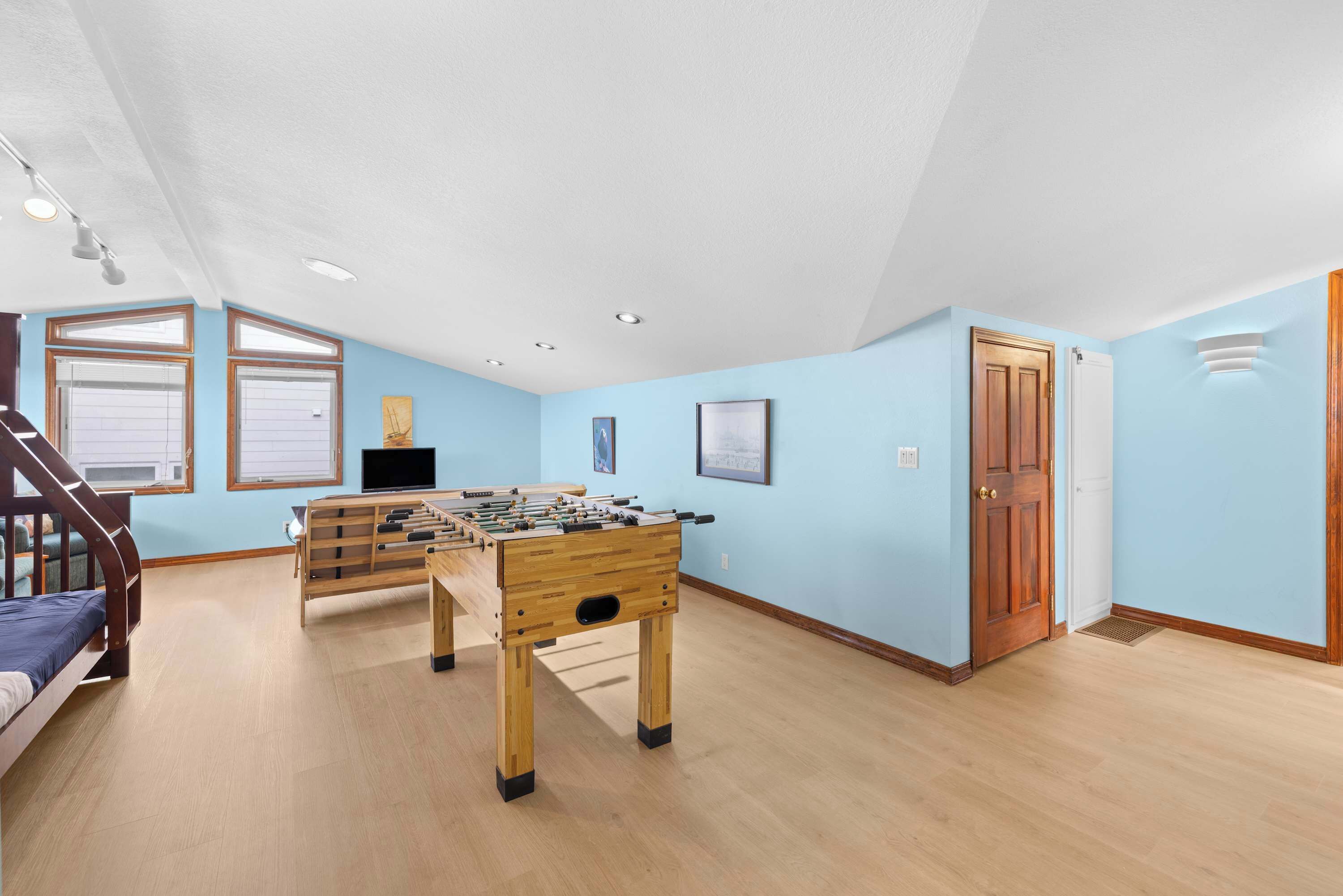 A room with a foosball table, a bed, and a door.